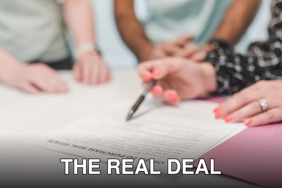 Close-up of people reviewing and signing an offer to purchase real estate document.
