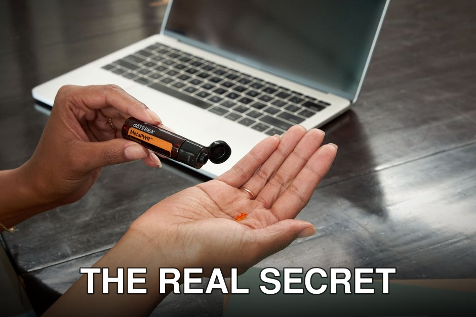 Close-up of a woman dispensing essential oil from a vial near a laptop, emphasizing relaxation and wellness.