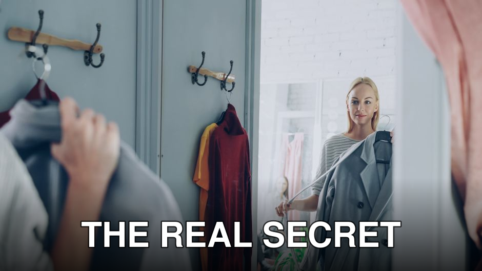 Woman holding a jacket, reflecting in a store mirror, deciding on her outfit.