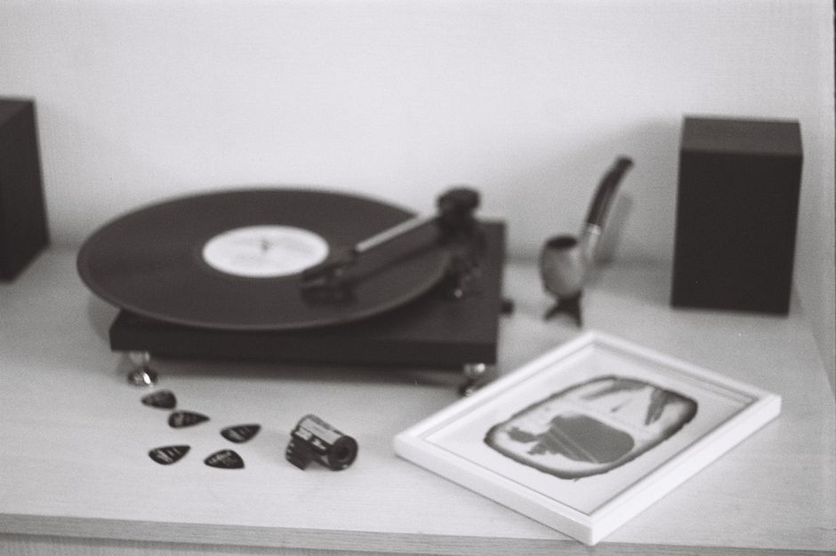 Monochrome vintage scene with vinyl record player, film roll, and framed art.