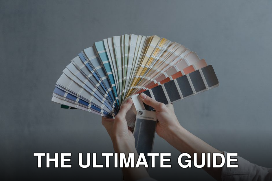 Hands holding a colorful fan of swatches on a gray backdrop, ideal for design themes.