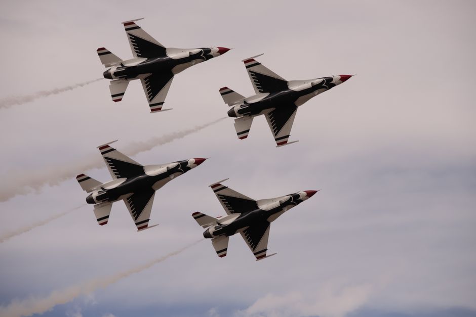 Four F-16 Thunderbirds perform an aerial maneuver against a cloudy sky.