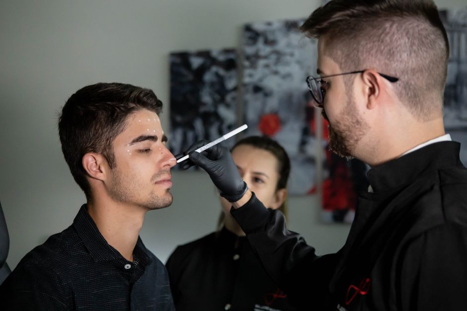 Surgeon marking patient's face for medical procedure in clinic setting.
