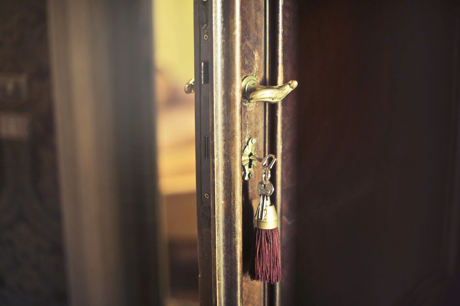 Closeup of key with tassel pendant in open weathered wooden door in old house