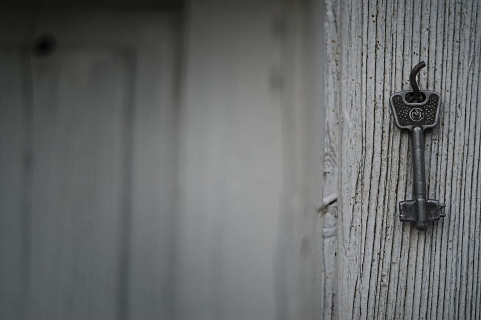 A vintage iron key hangs on a textured weathered wooden wall, evoking nostalgia and mystery.