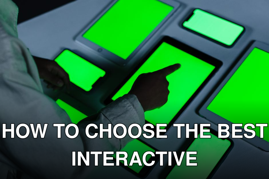 Person interacting with multiple green-screen electronic devices indoors.