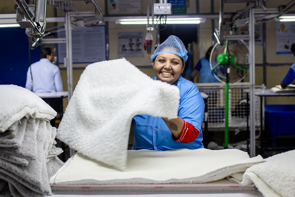 Cheerful textile factory worker organizing fabric indoors.