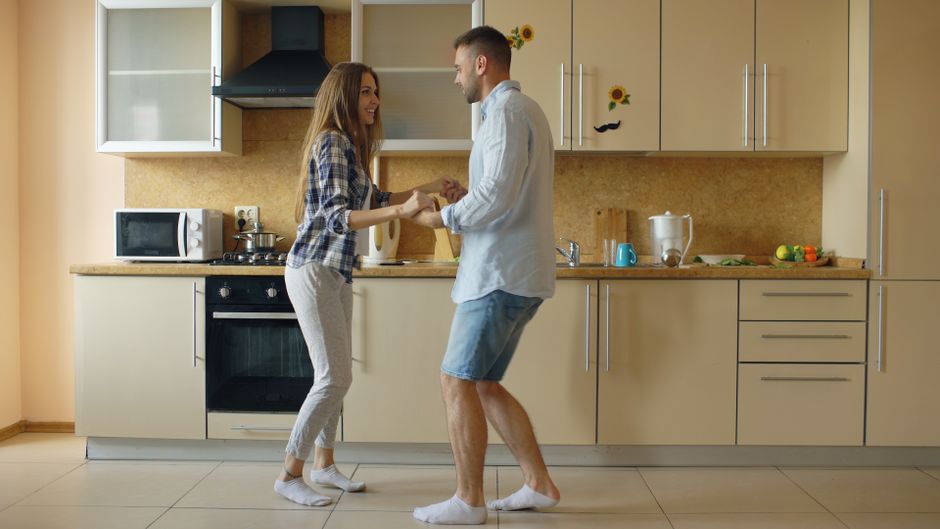 Couple joyfully dancing in the kitchen capturing a moment of happiness and love.