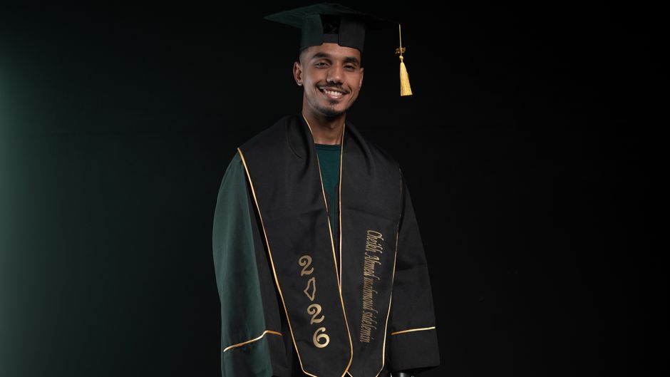 Portrait of a young male graduate smiling in cap and gown with class of 2026 inscription.