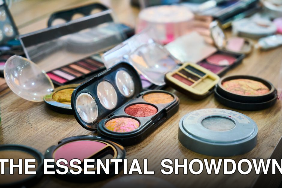 A variety of colorful makeup palettes and cosmetics organized on a wooden table.