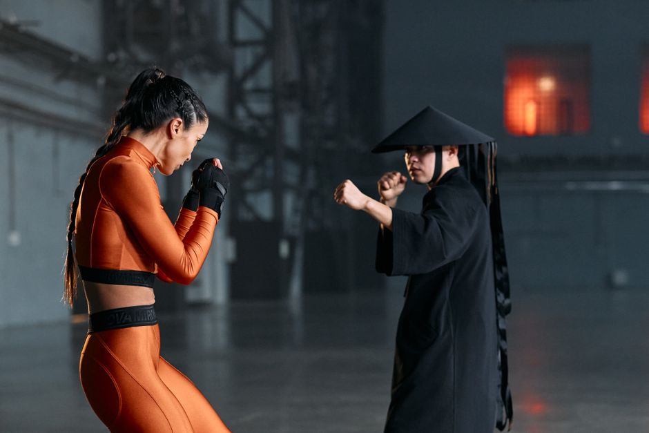 Cosplayers engage in a dramatic martial arts pose, inspired by game characters, indoors.