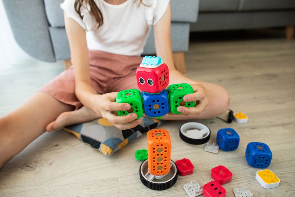 A child enjoys creativity indoors playing with a colorful robot toy, enhancing learning and fun.