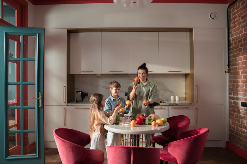 Mother with children preparing meals with fresh ingredients in a modern kitchen.